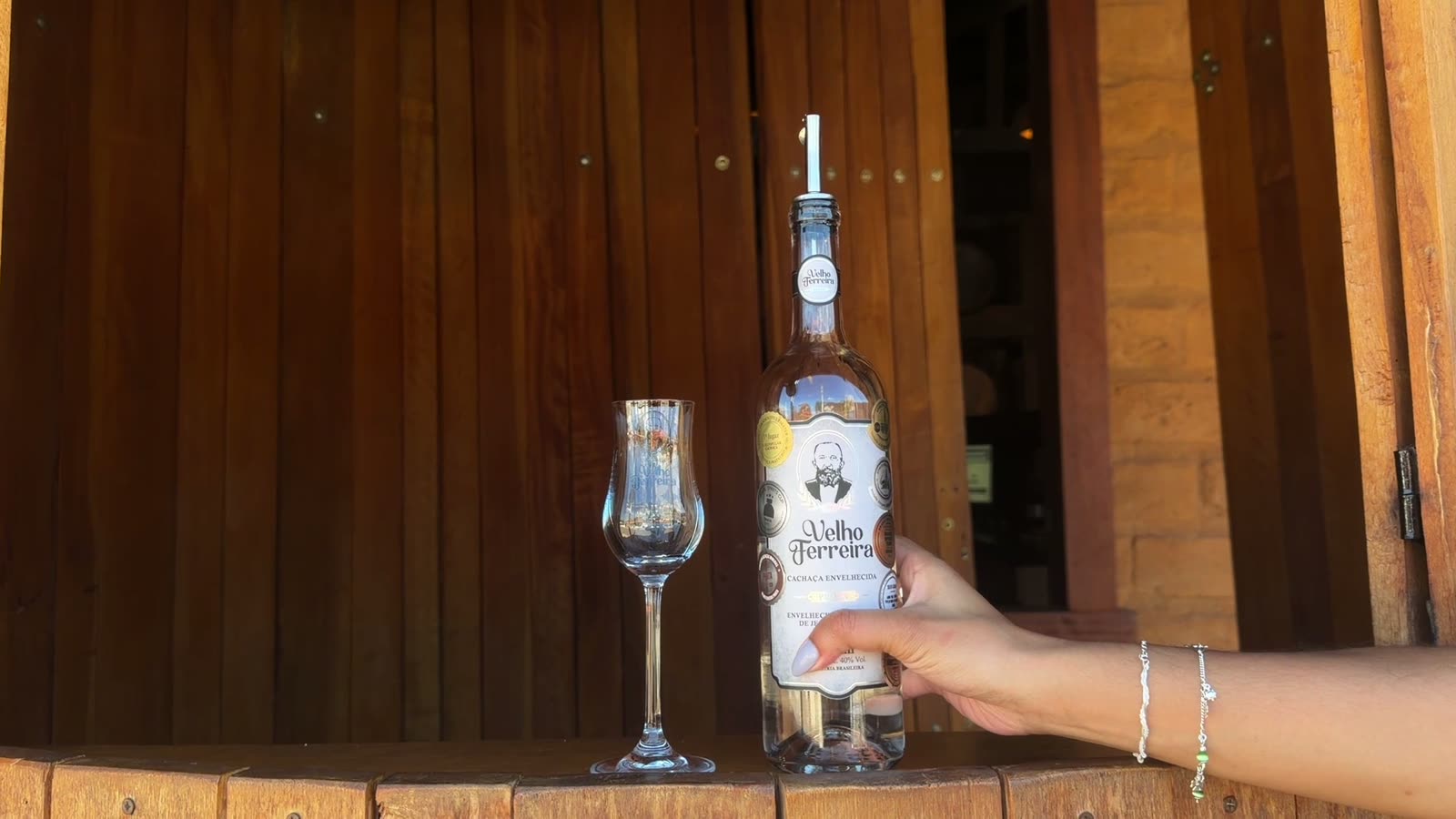 Dose de cachaça Velho Ferreira servida no balcão de madeira do alambique
